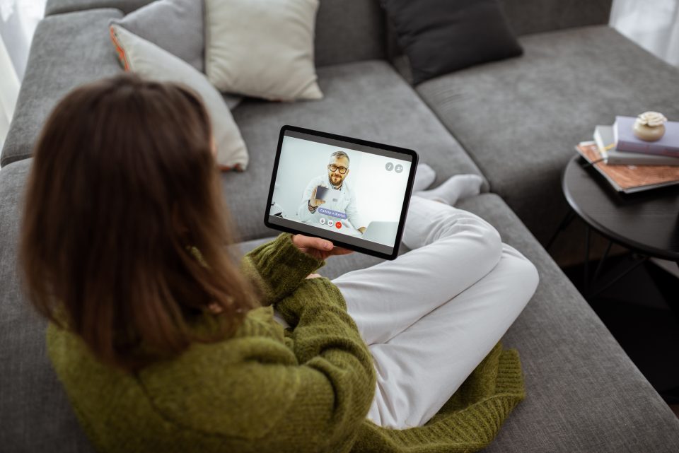 Woman talking with a doctor online using digital tablet, feeling bad at home. Concept of telemedicine and patient counseling online